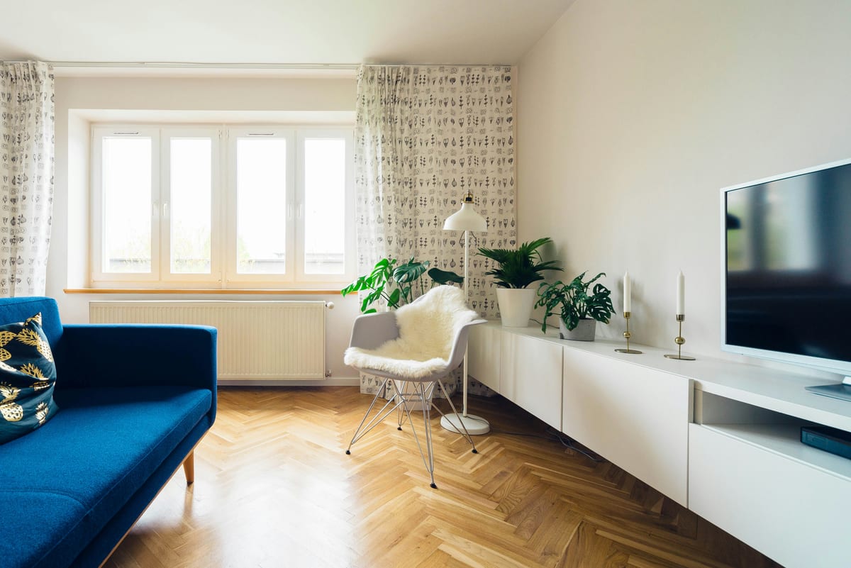 Sunlit bedroom with vintage decor and urban view through large window.